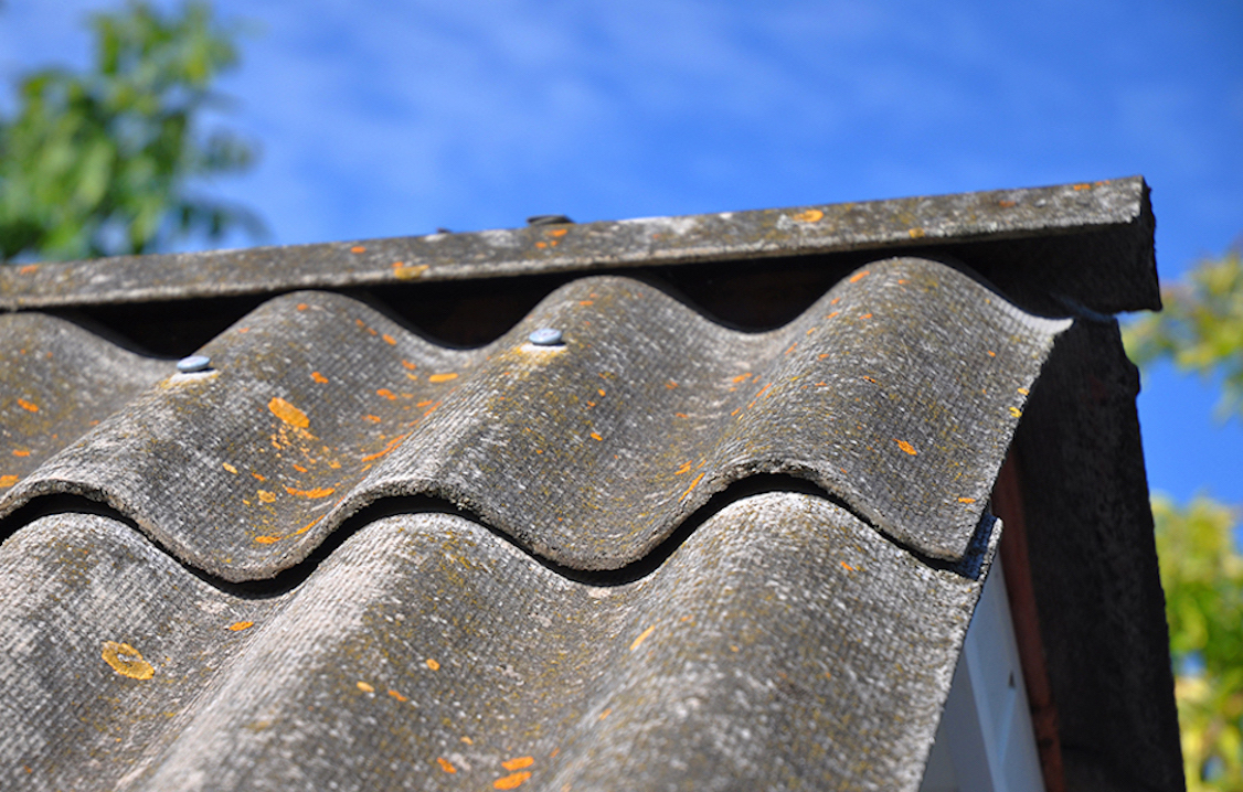 Blue sky over the dangerous asbestos old roof tiles